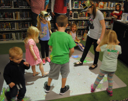 Photo of children playing with the MotionMagix floor projector. Images are projected onto the floor and are interactive.