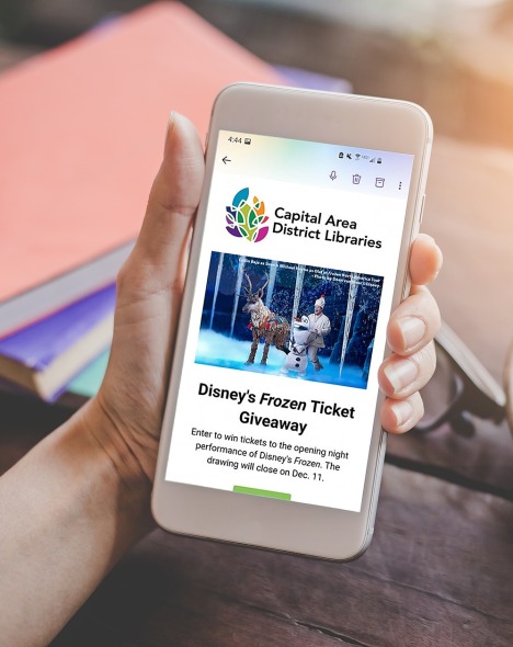 person holding mobile phone with information about a Disney Frozen ticket giveaway 