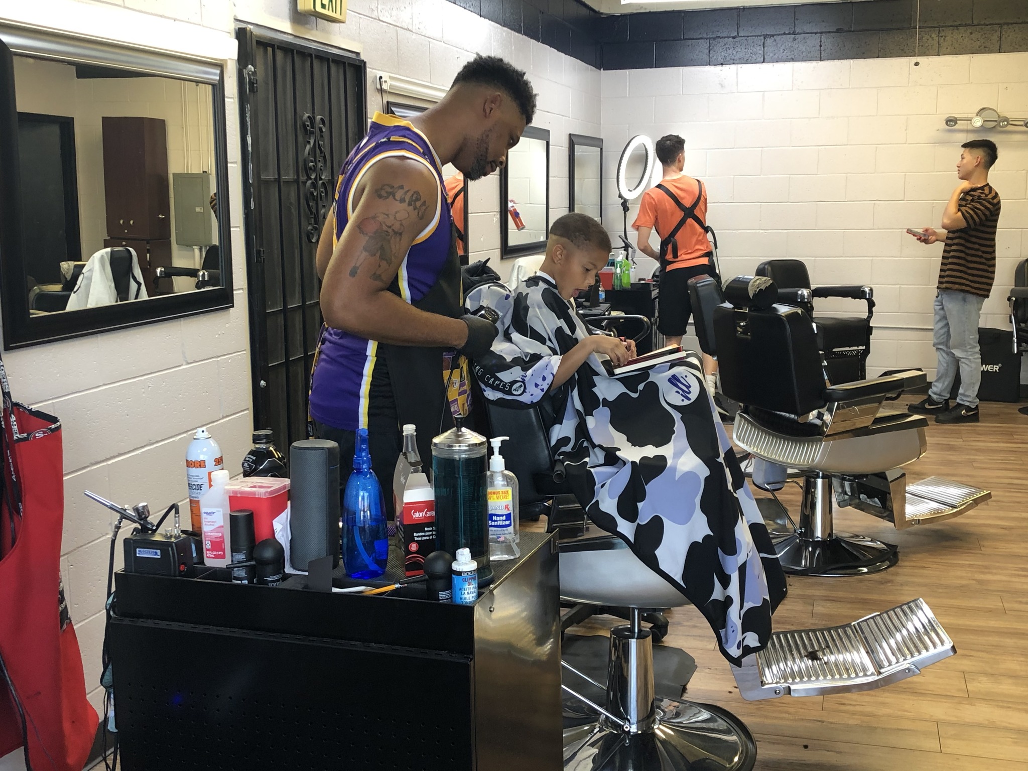 A young boy reading in a barbershop while a man cuts his hair