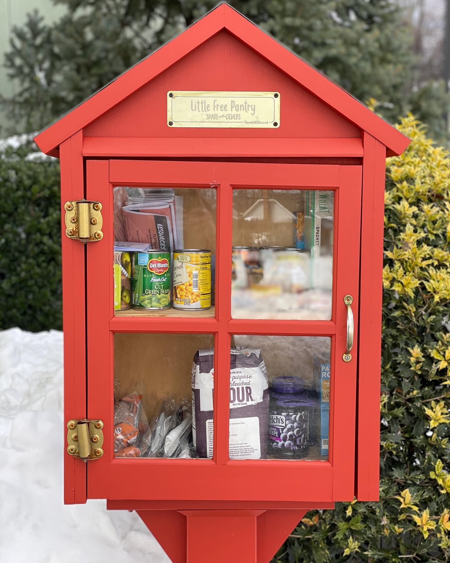 Closeup of an outdoor A-frame wooden little free pantry with food inside