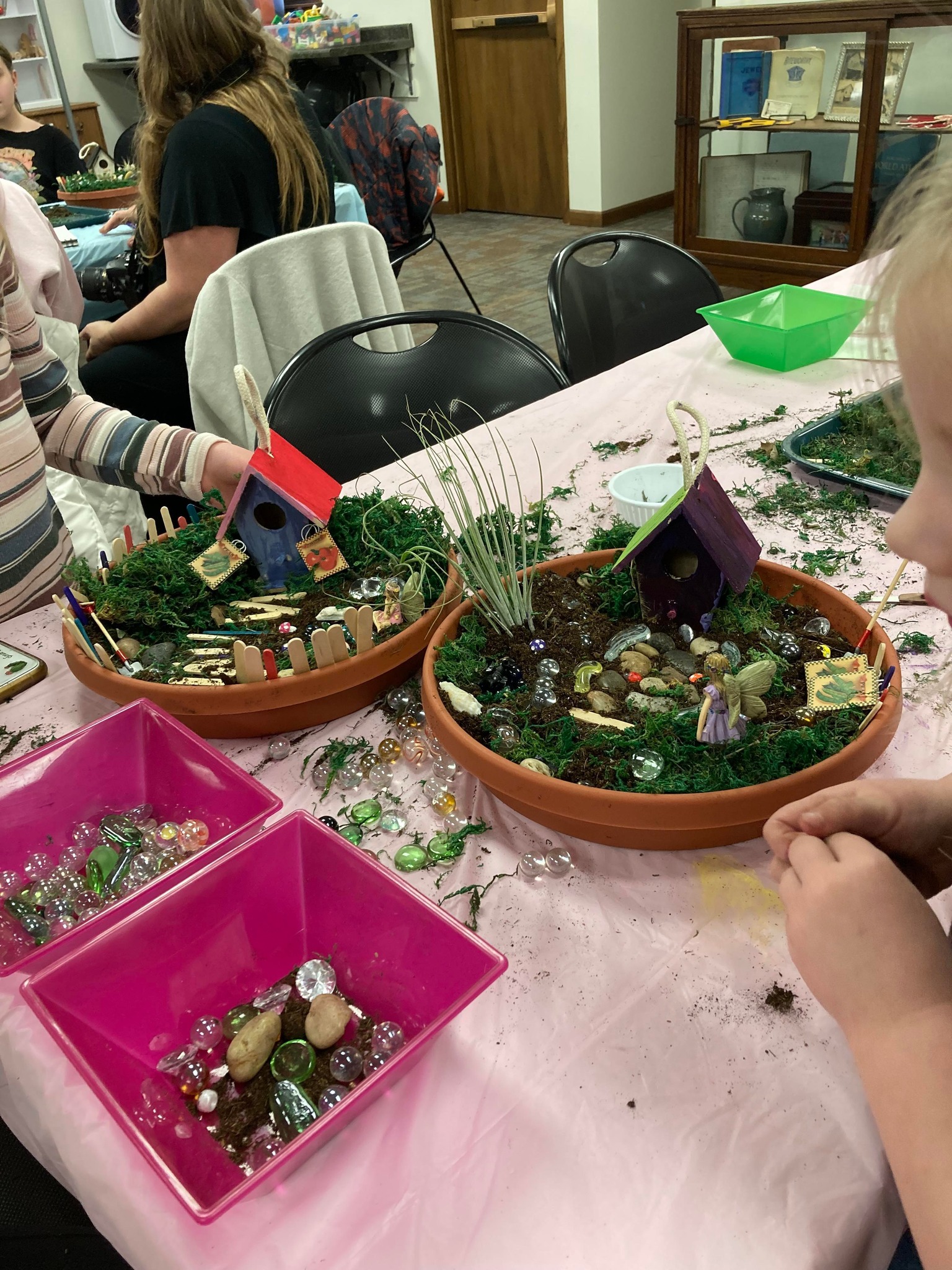 Close-up of two children at a table creating fairy gardens