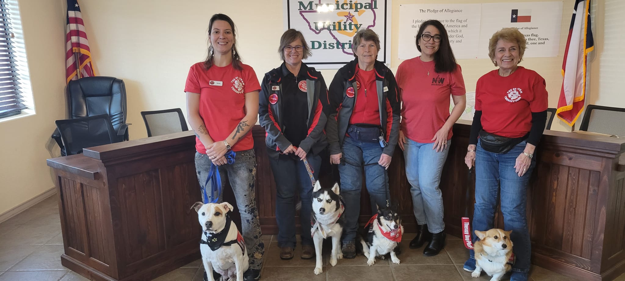 group of smiling people with four therapy dogs