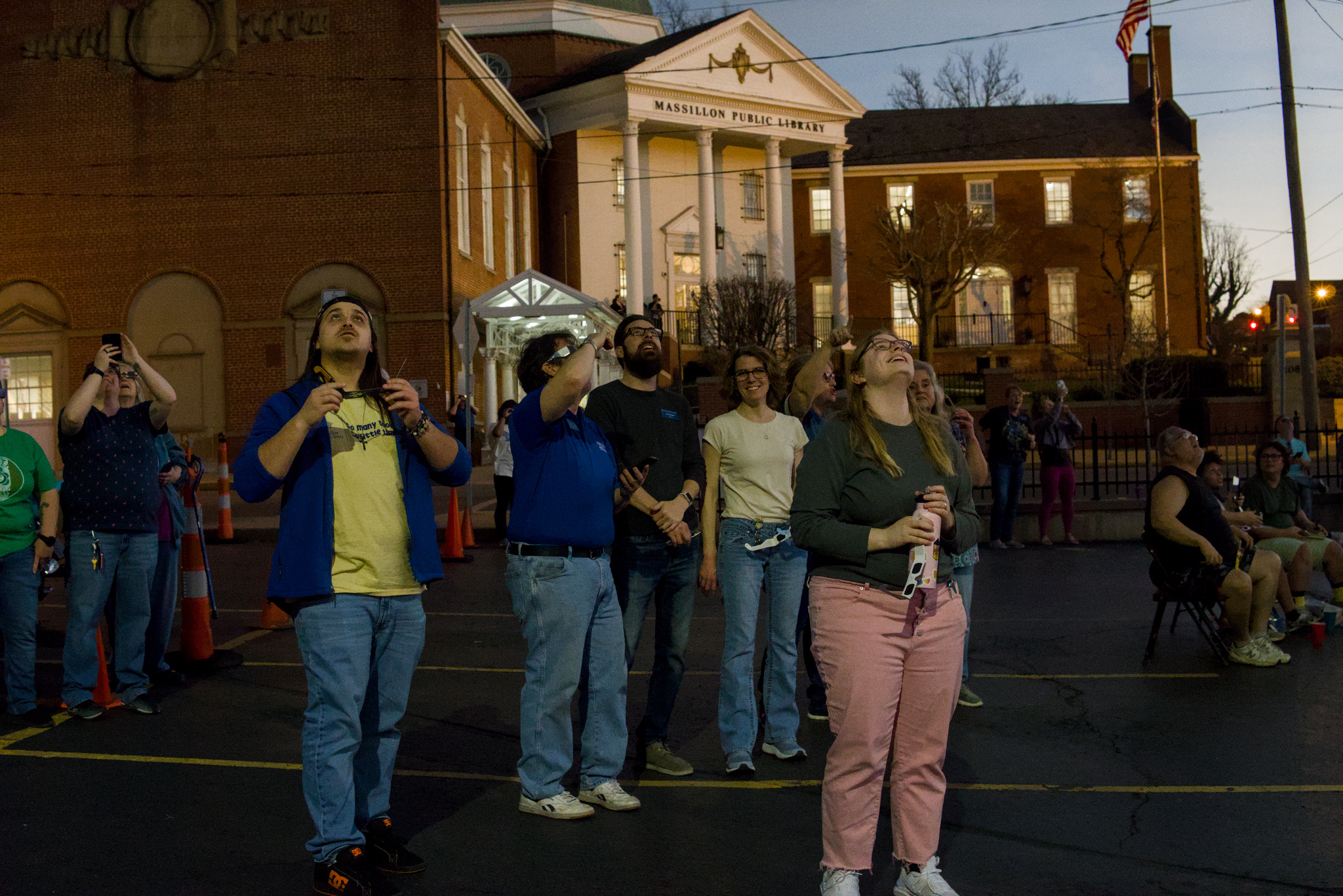 group of people wearing solar glasses and watching the eclipse outside of a library