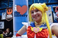Woman in Sailor Moon costume stands in front of i heart libraries banner