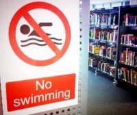 No Swimming sign with book stacks in the background