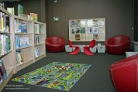 Photo of children's area with chairs, bookshelves and carpet.