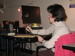 Woman sits at a computer writing some notes