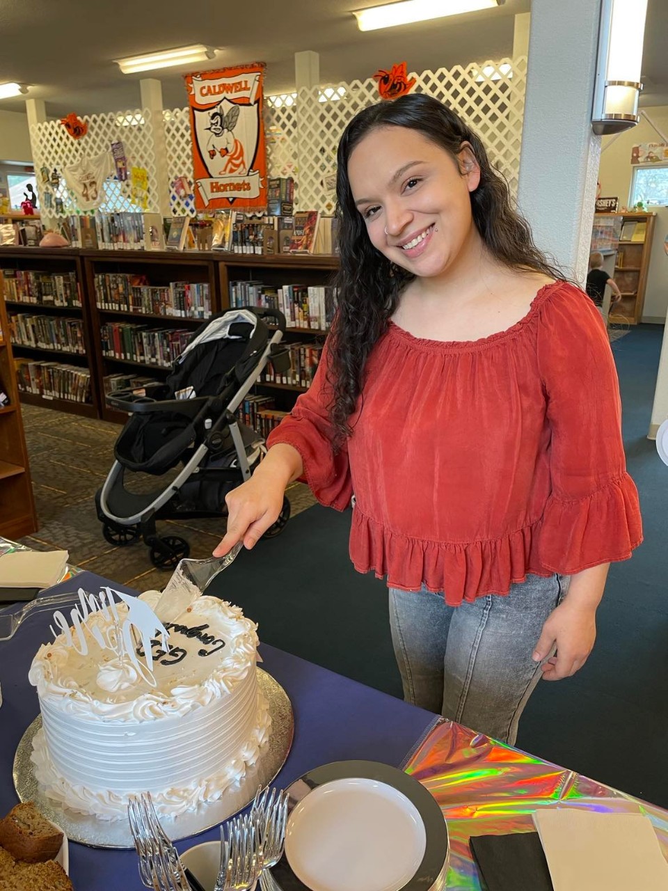 a smiling woman cutting a graduation cake