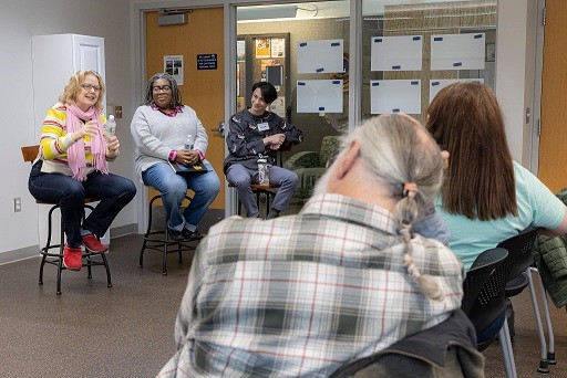 4 patrons and a facilitator sitting in a circle talking