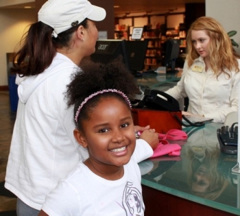 Girl and adult receiving customer service at library desk