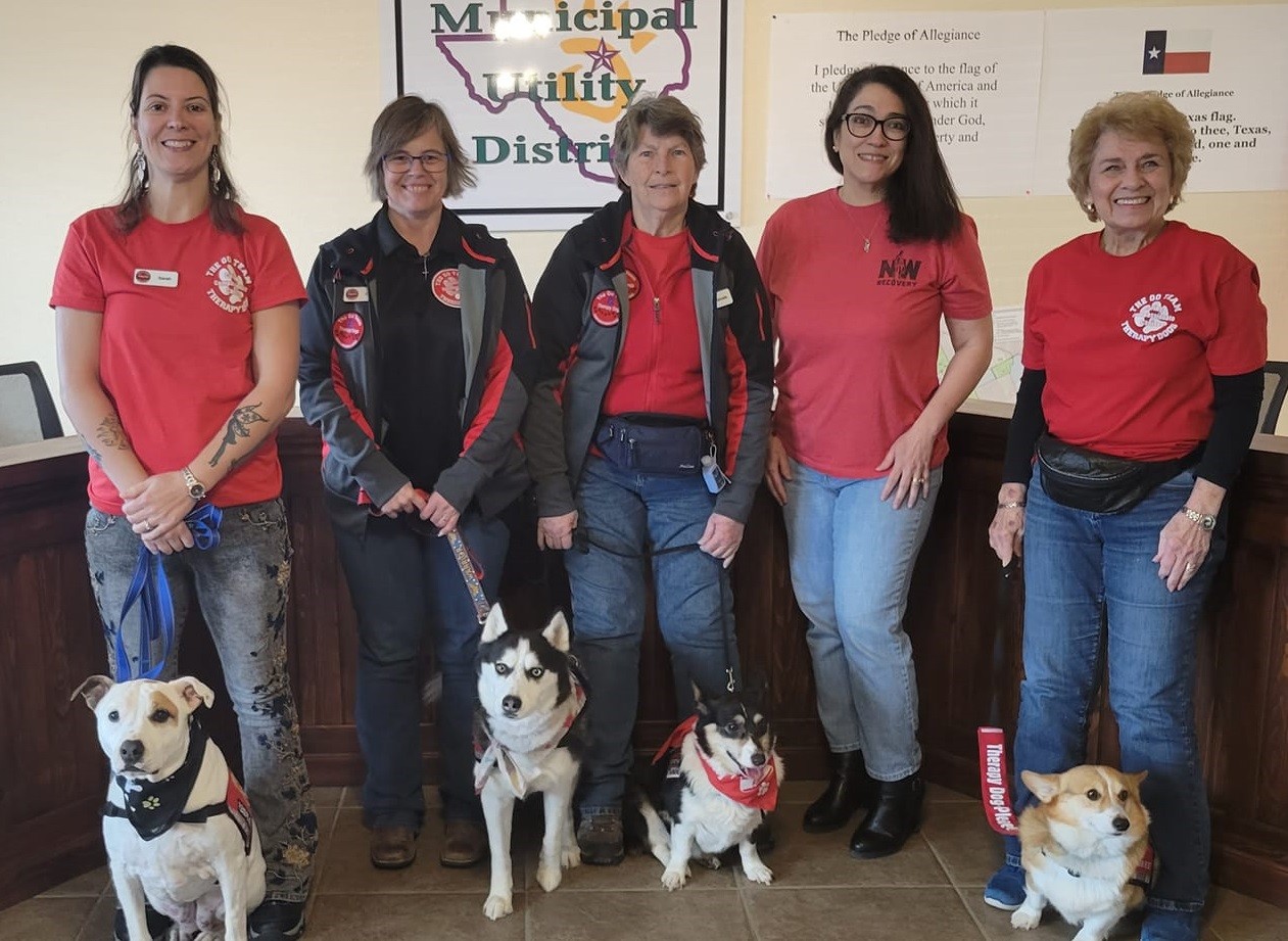group of smiling people with four therapy dogs