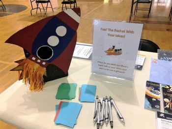 Large cardboard rocket ship, which beckoned people to “Fuel the Rocket with Your Ideas!”  to respond to the question “what do you wish our library had?” 