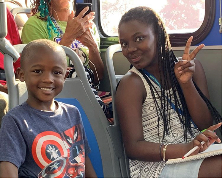 two smiling kids seated on a bus 