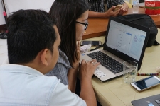 One adult helping someone on a laptop