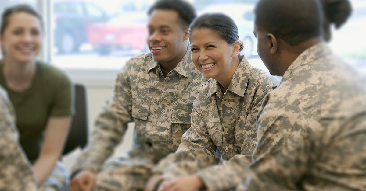 group of several people in military uniforms chatting and smiling 