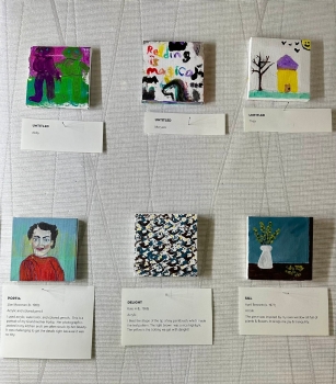 Close-up of six tiny square painted canvasses with title and author cards